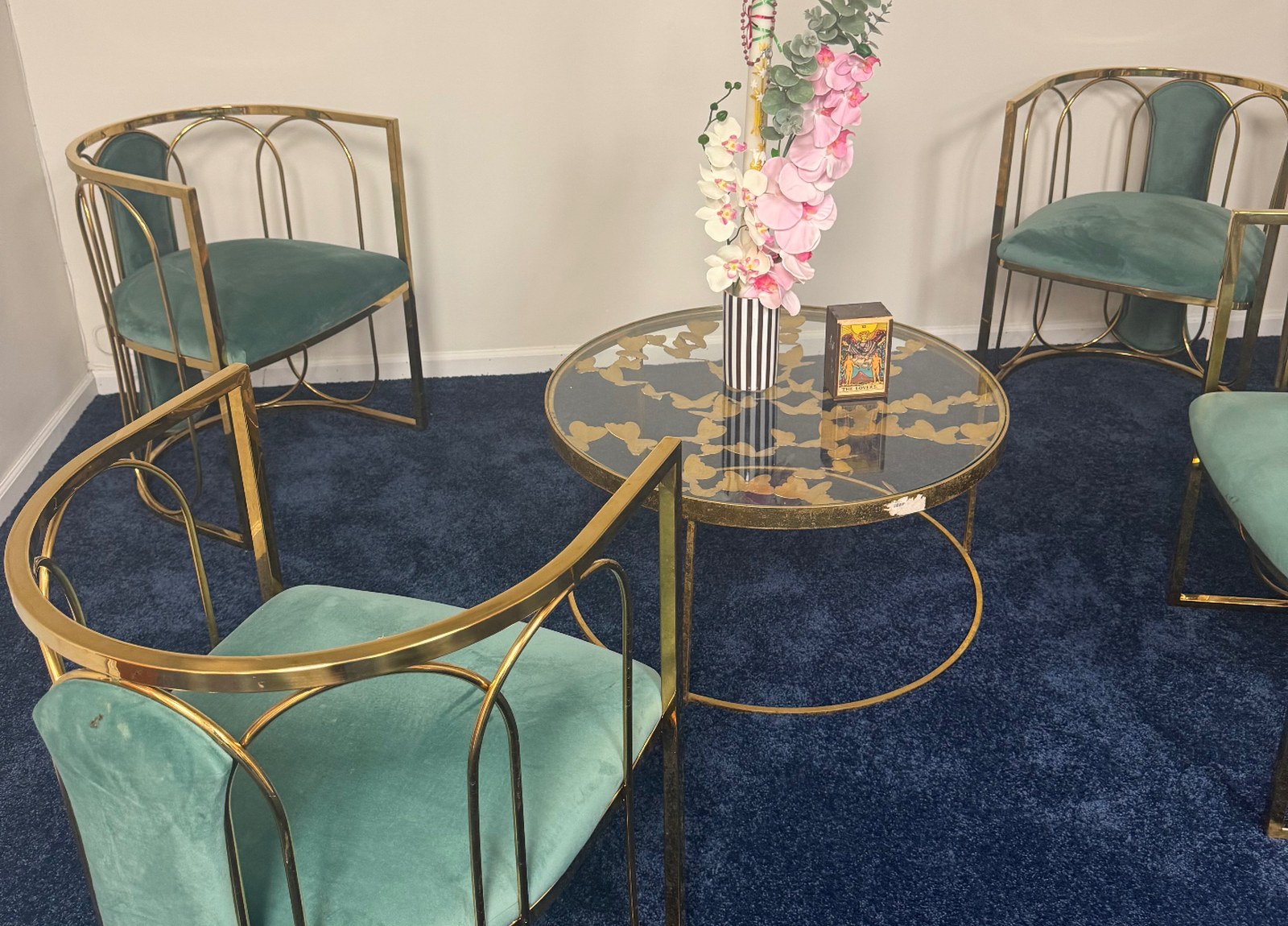 Green velvet chairs around a gold and glass reading table in the Chicago studio